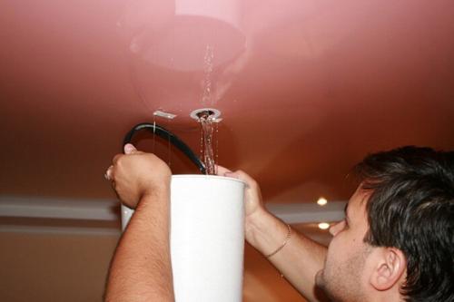 Ремонт натяжного потолка после затопления. Слив воды через отверстие для светильника